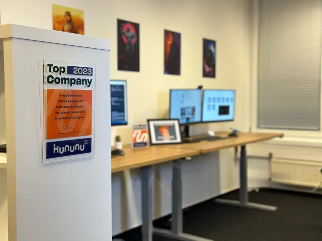 Die kununu-Auszeichnung Top Company an der Wand über den Arbeitsplätzen im Büro