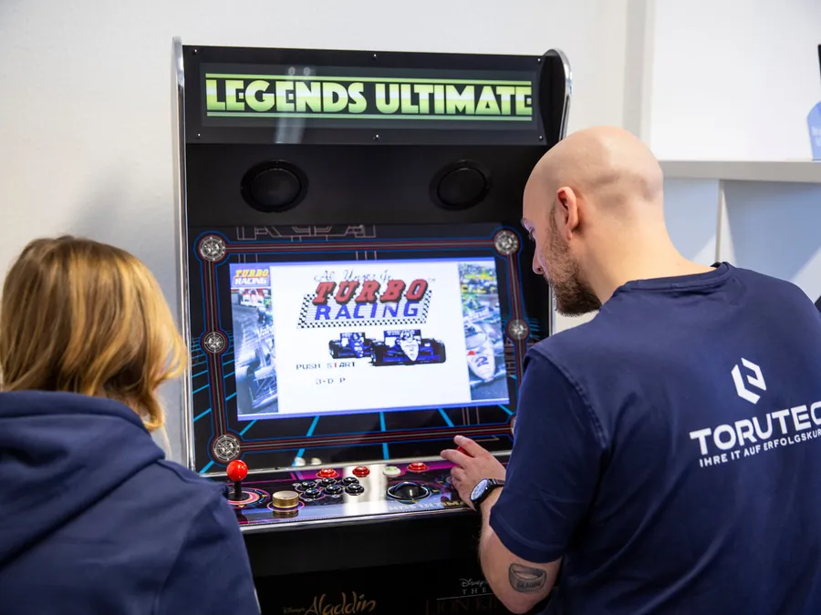 Zwei Kollegen spielen am Arcade-Automaten im Büro