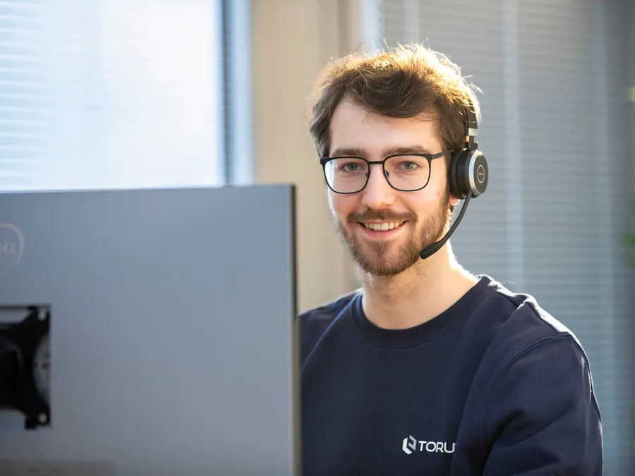 Ein Kollege mit Headset am Laptop im Support