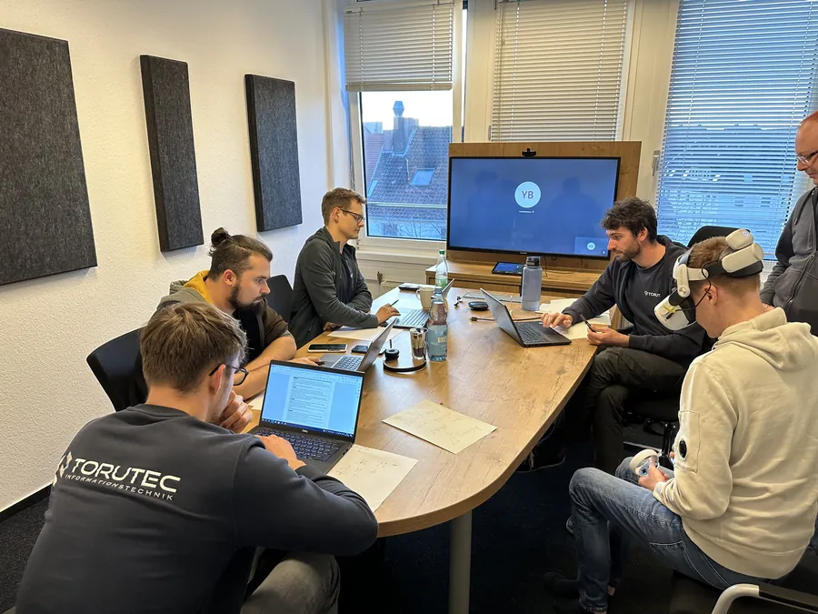 Das Team im Besprechungsraum, ein Kollege testet eine VR-Brille